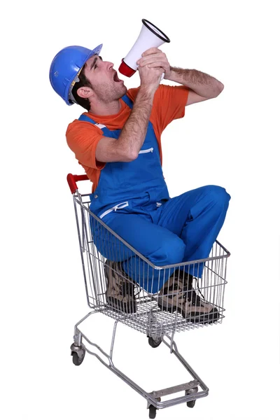 Comerciante sentado em um carrinho de compras e gritando em um megafone — Fotografia de Stock