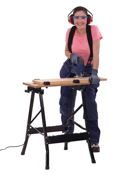Female capenter cutting plank with electric saw — Stock Photo, Image