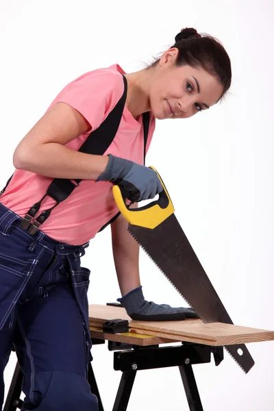 Junge Frau sägt ein Holzbrett — Stockfoto