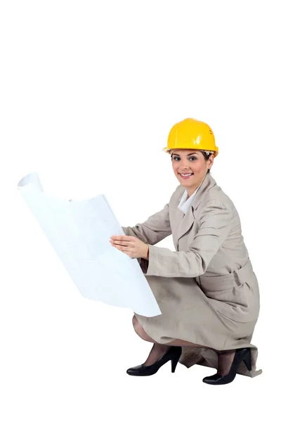 Female architect kneeling with blueprints — Stock Photo, Image