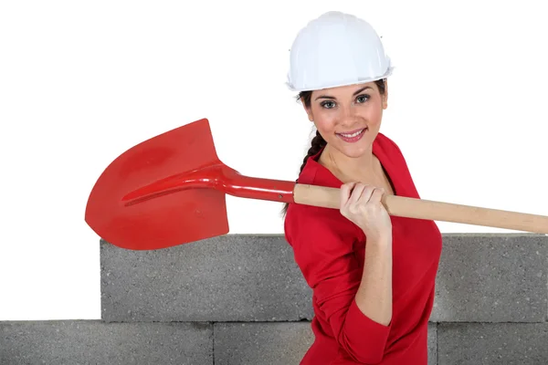 Woman stood by unfinished wall with spade — Stock Photo, Image