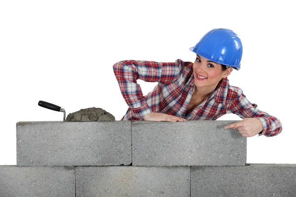 Retrato de jovem pedreiro feminino apontando para a parede de concreto — Fotografia de Stock