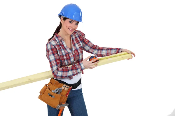 Female carpenter measuring a piece of wood. — Stock Photo, Image