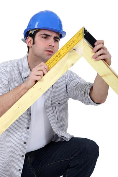 Carpinteiro medindo uma moldura de madeira — Fotografia de Stock