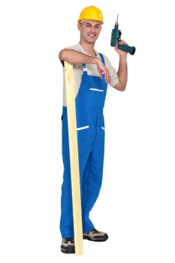 Tradesman holding an electric screwdriver and a wooden plank clipart