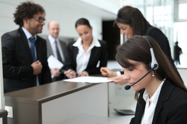 Businesspeople crowding around the reception area of their company clipart