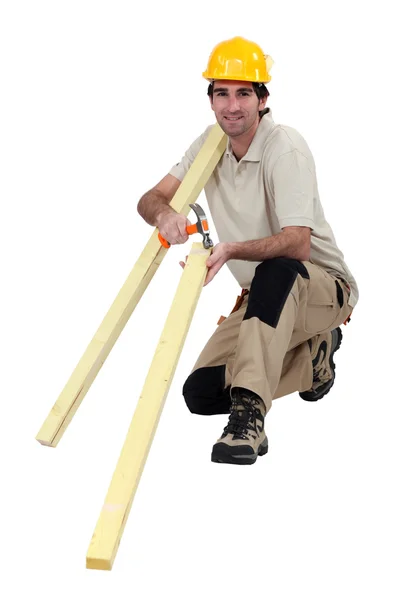 Trabalhador da construção segurando pranchas de madeira e um martelo — Fotografia de Stock