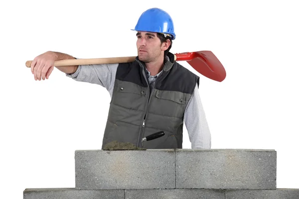 Man with spade stood by unfinished wall — Stock Photo, Image