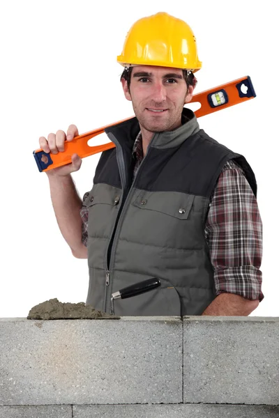 Stonemason standing before a wall and carrying a spirit level — Stock Photo, Image