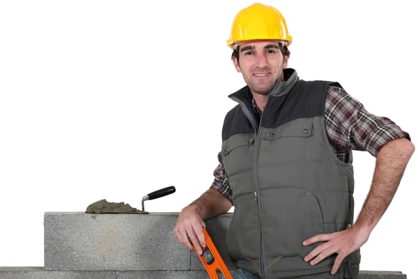 Bricklayer posing near wall with arm akimbo — Stock Photo, Image
