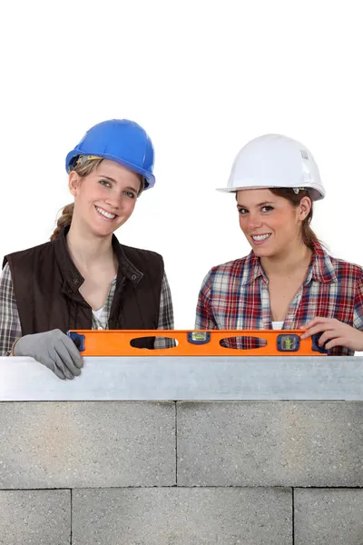 Two woman stood by wall holding spirit level — Stock Photo, Image