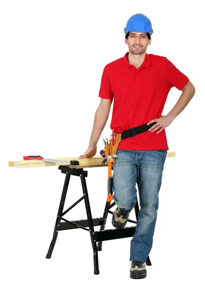 Man with wood, a workbench and saw — Stock Photo, Image