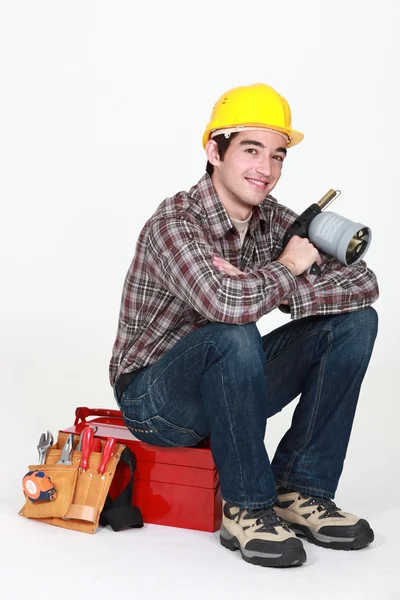 Tradesman tenant un chalumeau et assis sur sa boîte à outils — Photo