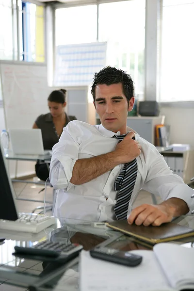 Człowiek siedział w biurze, dostosowując jego krawat — Zdjęcie stockowe