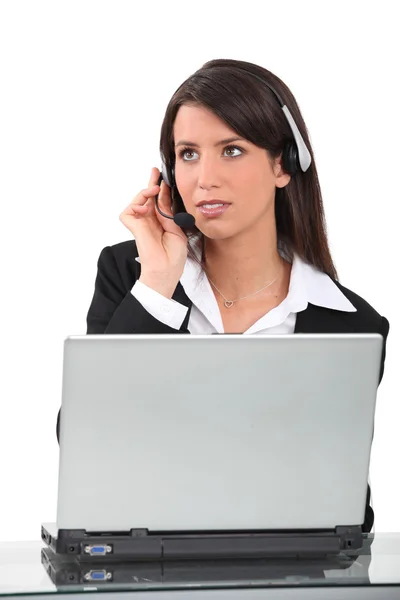 Mujer con auricular de teléfono sentado en frente de la computadora portátil —  Fotos de Stock