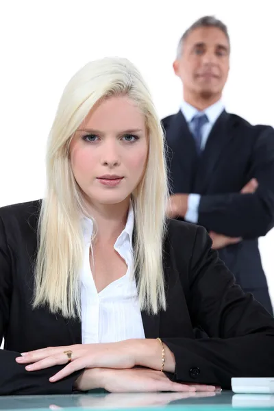 Junge blonde Geschäftsfrau mit älterem Mann im Hintergrund — Stockfoto