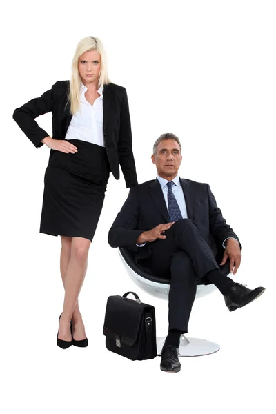 Бізнесмен сидить у кріслі поруч зі своїм гламурним помічником — стокове фото