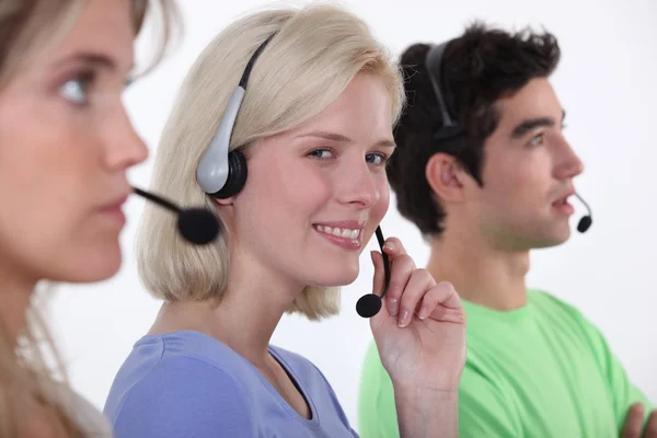 Tre lavoratori del call center seduti di fila — Foto Stock