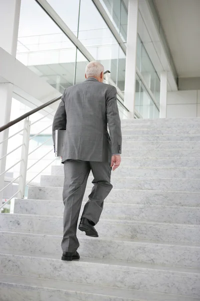 Grauhaariger Geschäftsmann steigt Stufen hinauf — Stockfoto
