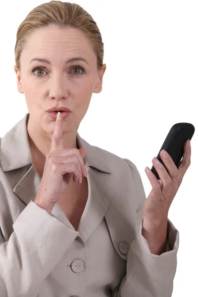 Frau zeigt Ruhe an, während sie ein Telefon in der Hand hält — Stockfoto