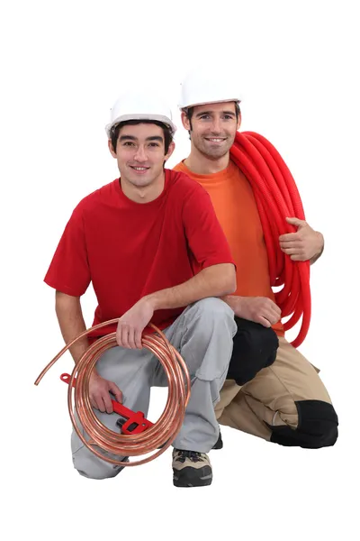 Plumbers with traditional copper and modern plastic pipe — Stock Photo, Image