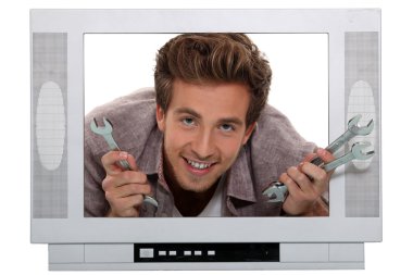 Young man with spanners poking his head through a mock up TV set clipart