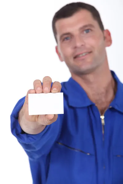 Muž v modrých montérkách drží vizitka levice prázdné pro vaše detaily — Stock fotografie