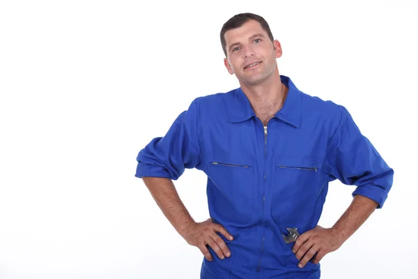 Студийный снимок человека в синем комбинезоне с руками на бедрах — стоковое фото