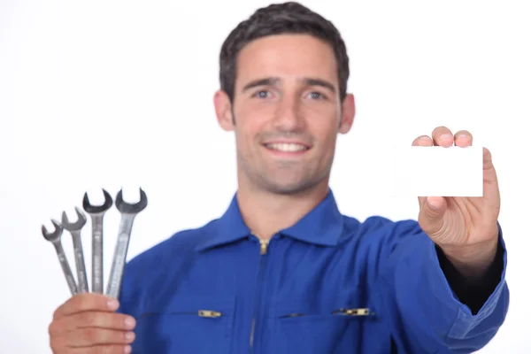 Mechanic holding selection of spanners and business card — Stock Photo, Image