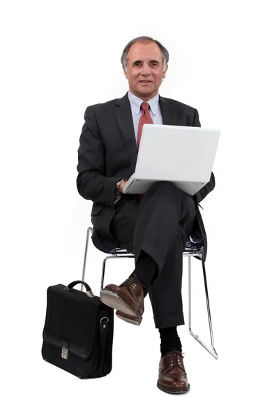 Orta yaşlı işadamı dizüstü kullanarak sandalyeye oturdu — Stok fotoğraf