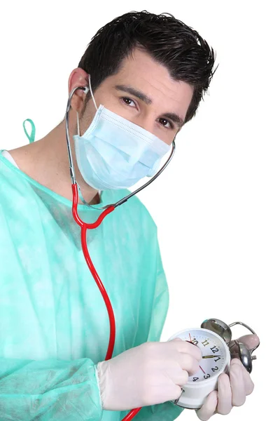 A surgeon listening to an alarm clock's heartbeat — Stock Photo, Image