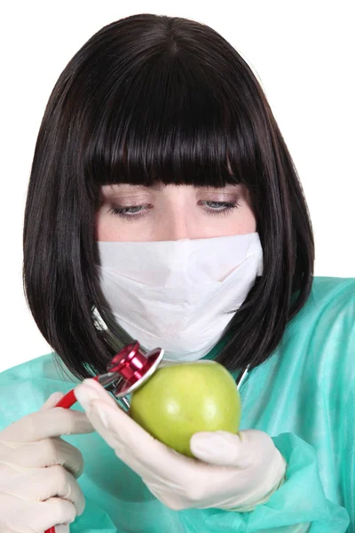 Sjuksköterska undersöker ett äpple med stetoskop — Stockfoto