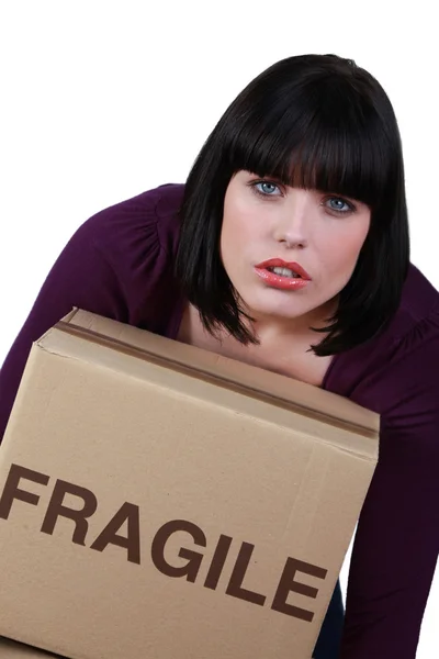 Kvinna som bär en tung låda märkt bräckliga — Stockfoto