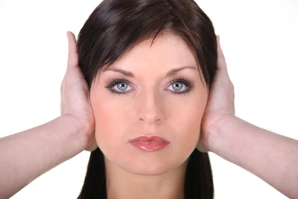 Mujer joven de cabello castaño cubriéndose las orejas —  Fotos de Stock