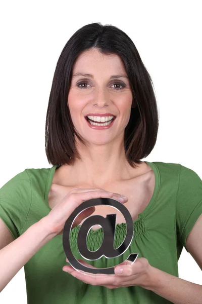 Mujer sonriente sosteniendo el signo de arobase —  Fotos de Stock