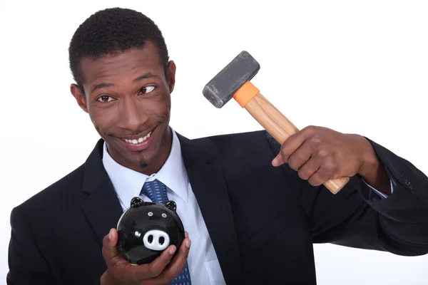 Man probeert te breken in een spaarvarken met een hamer — Stockfoto