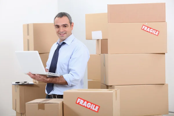 Uomo in giacca e cravatta circondato da pile di scatole — Foto Stock