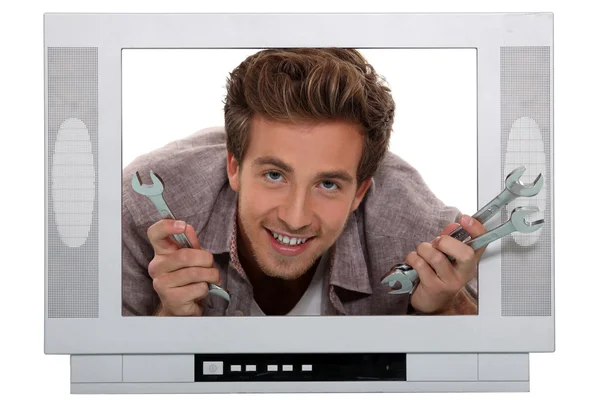 Mladý muž s klíče strká hlavu přes vzorovou televizi — Stock fotografie