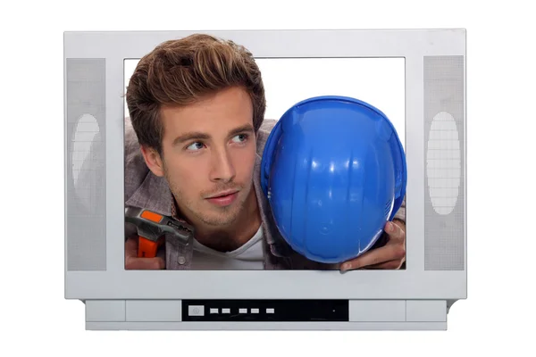Young man and his hard hat stuck in a television screen — Stock Photo, Image
