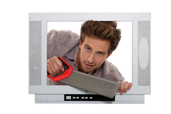 Man with a saw inside a television set — Stock Photo, Image