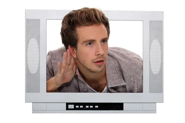 Young man through a TV screen listening something carefully — Stock Photo, Image