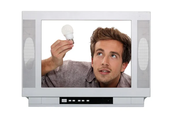 stock image Man fitting light bulb inside television