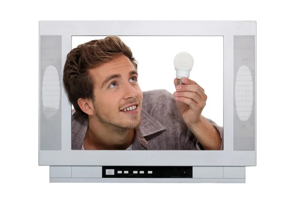 Hombre encajar bombilla dentro de la televisión — Foto de Stock