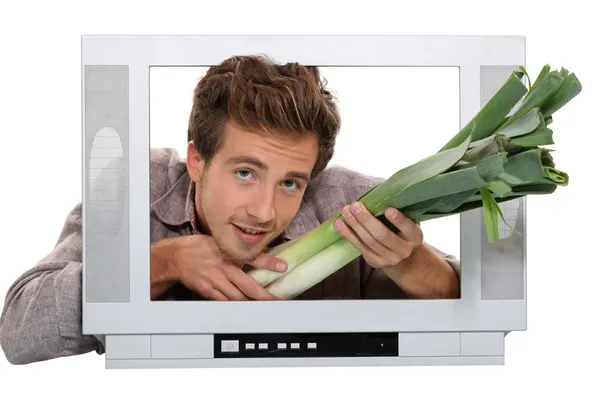 Un homme donnant des poireaux à travers un écran — Photo