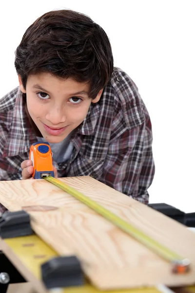 Хлопчик столяр вимірює деревину — стокове фото