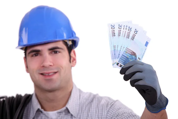 Construction worker holding up money — Stock Photo, Image