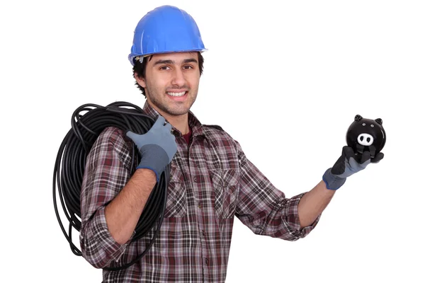 Tradesman holding electric cabling and a piggy bank — Stock Photo, Image