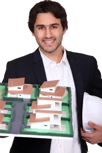 Jovem arquiteto segurando um modelo de um edifício — Fotografia de Stock
