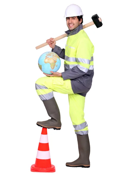 Road worker holding a hammer on his shoulder and a globe — Stock Photo, Image