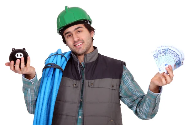 Šťastný mladý instalatér držící bankovky a prasátko — Stock fotografie